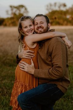 a man and woman hug each other while standing in the middle of an open field