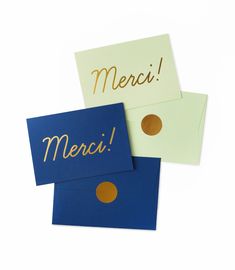 two greeting cards with the words merci and merci written in gold on them