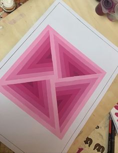 an art project is being made using pink and white paper, which are cut into triangles