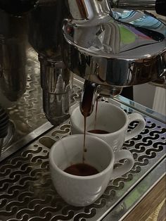 espresso being poured into two cups in front of an espresso machine