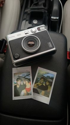 a camera sitting on top of a car seat next to two polaroid pictures and a cell phone