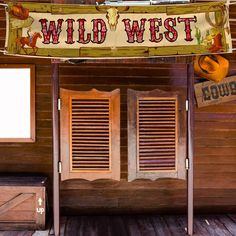 a sign that says wild west hanging from the side of a wooden building with shutters