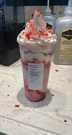 a cup filled with whipped cream and red sprinkles on top of a counter