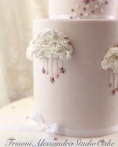 a three tiered cake with white flowers and stars on the top is decorated in pink frosting