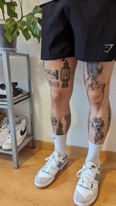 the legs and ankles of a man with tattoos on his body, wearing white sneakers