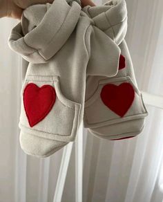 someone is holding two pairs of baby shoes with hearts on the inside, and one pair has been folded up