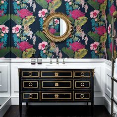 a black and gold dresser with flowers on it in front of a wallpapered bathroom