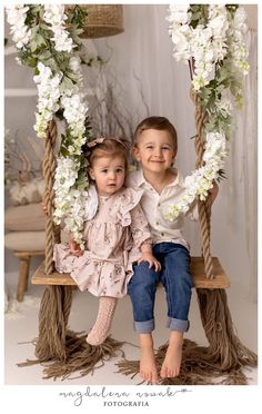 two children sitting on a swing with flowers