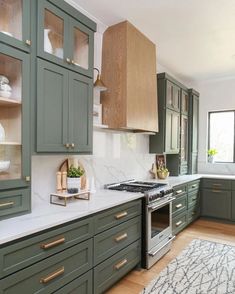 a kitchen with green cabinets and white counter tops, an area rug on the floor