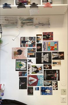 a white wall covered in pictures and magnets next to a shelf with books on it