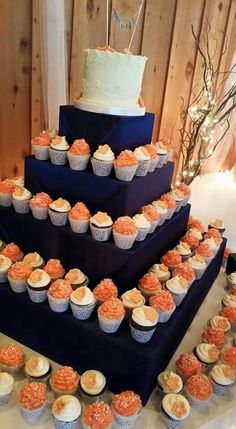 a three tiered cake with cupcakes on the bottom and side, along with other desserts