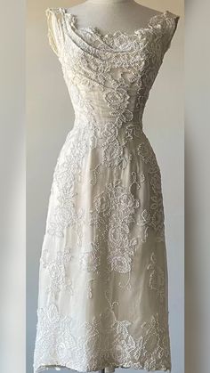 a white dress on a mannequin with an open neckline and lace detailing