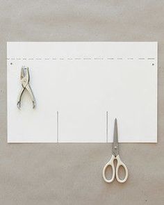 pair of scissors sitting on top of a white piece of paper next to each other