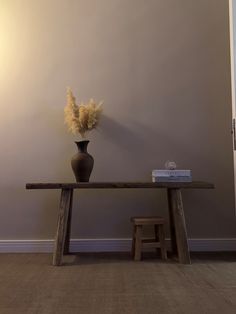 a wooden table with a vase on it and a book sitting on top of it