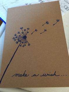 a dandelion with the words make a wish written in blue ink on brown paper