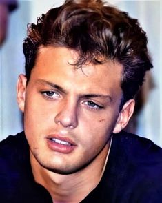 a close up of a person wearing a black shirt and looking at the camera with a serious look on his face