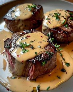 three steaks covered in gravy on a plate