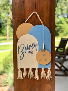 a wooden sign hanging from the side of a pole with tassels on it