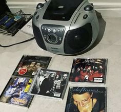 there are many cd's on the floor next to an mp3 player and speakers