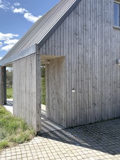 a wooden building sitting on the side of a road next to a lush green field