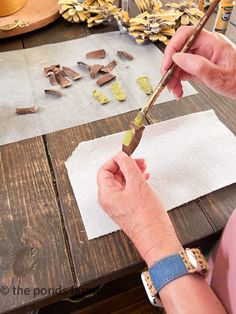 an older woman is working on crafts with wood shavings and paintbrushes