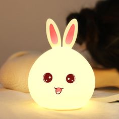 a white lamp with a bunny face on it and a black cat in the background