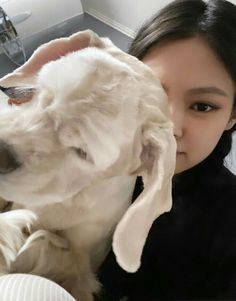 a woman holding a white dog in her arms and looking at the camera with an intense look on her face