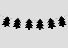 a line of black trees hanging from a string on a gray background with the words christmas written below it