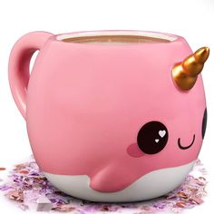 a pink mug with a gold horn on the side and some confetti around it