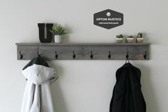 a coat rack with two coats hanging from it and three potted plants on the wall