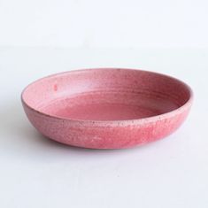 a pink bowl sitting on top of a white table