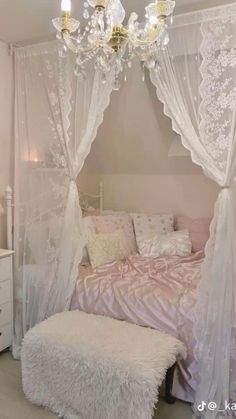 a bedroom with a white canopy bed and chandelier hanging from it's ceiling