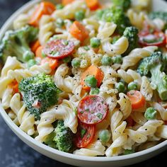 a white bowl filled with pasta and veggies on top of a black table