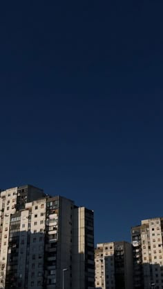 an airplane is flying in the sky over some tall buildings with no one on it