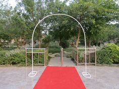 a red carpet is on the ground in front of an iron arch with two white arches