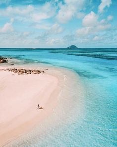 an aerial view of a beach with blue water and white sand, surrounded by small islands