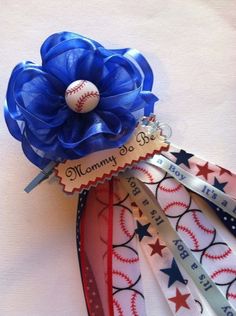 a baseball themed hair clip with a blue flower on it's top and red, white, and blue ribbons attached to it