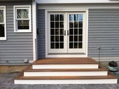 a house with steps leading up to the front door and side entry area, which has glass doors on both sides