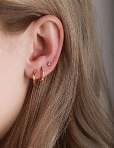 a close up of a woman's ear with two small gold hoops on it