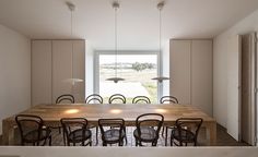 a dining room table surrounded by chairs in front of a large window with lights on it