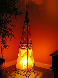 a lamp sitting on top of a table next to a potted plant in front of a red wall