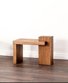 a wooden bench sitting on top of a hard wood floor next to a white wall