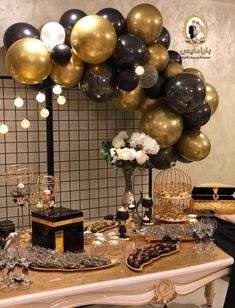 a table topped with lots of black and gold balloons