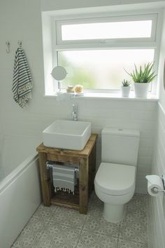 a bathroom with a toilet, sink and bathtub next to a window in it