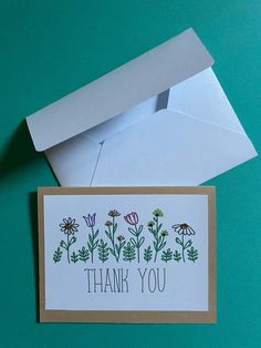 a thank you card with flowers on it and an envelope in the background that says, thank you