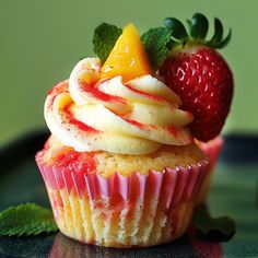 a cupcake with white frosting and strawberries on top