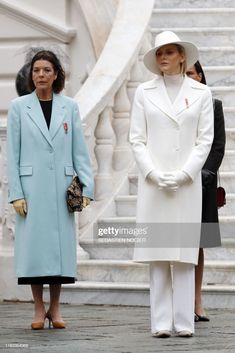 two women standing next to each other wearing coats and hats