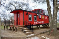 a red building with stairs leading up to it's entrance and trees in the background