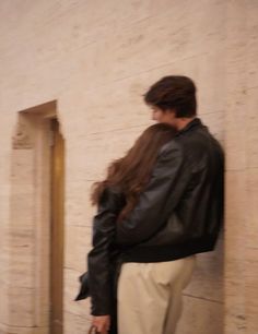 a woman standing in front of a wall with her back to the camera and looking at something