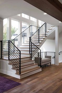 there is a stair case in the middle of this living room with hardwood floors and white walls